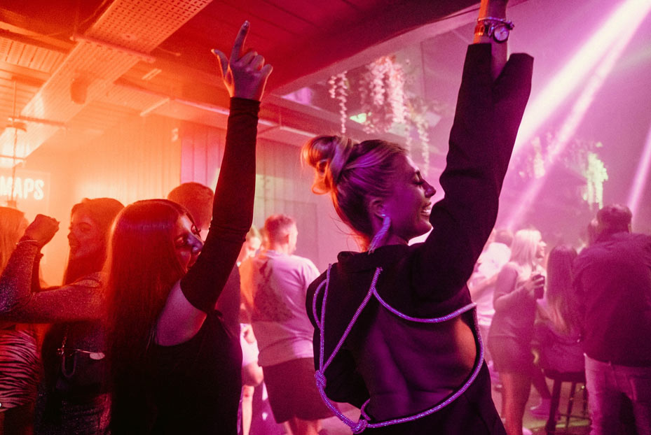 Girls dancing with hands in the air inside 54 Liverpool