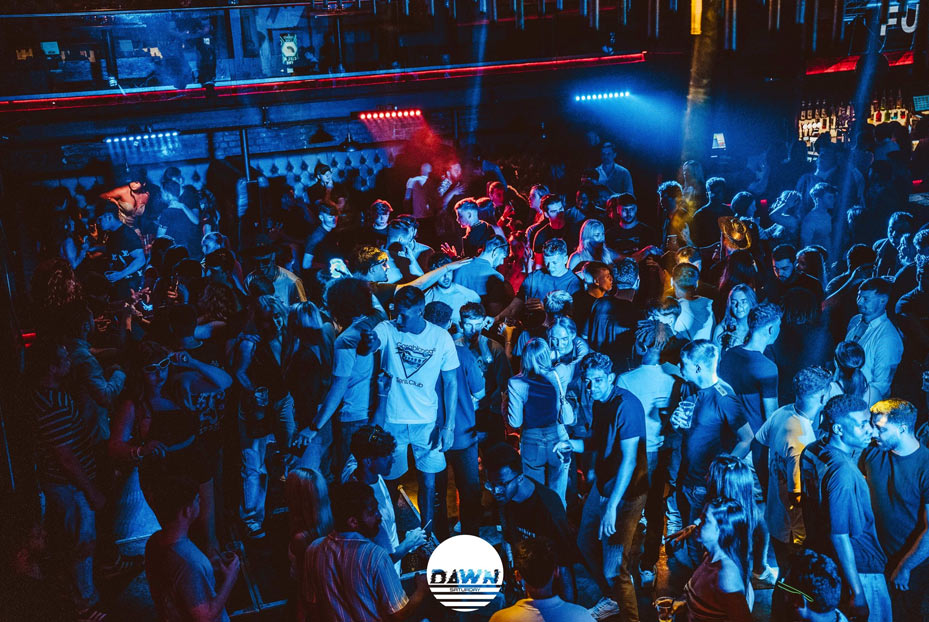 Clubbers dancing inside the Fusion club under low lighting